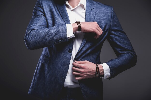 il ritratto del modello dell'uomo d'affari alla moda dei pantaloni a vita bassa alla moda bello si è vestito in vestito blu elegante su gray