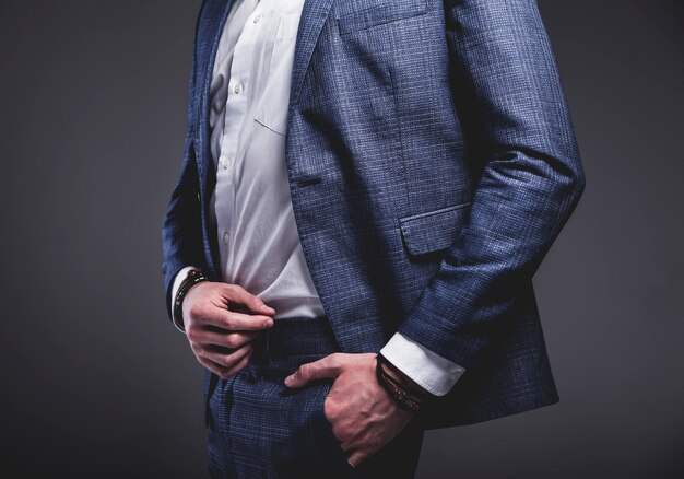 il ritratto del modello dell'uomo d'affari alla moda dei pantaloni a vita bassa alla moda bello si è vestito in vestito blu elegante su gray
