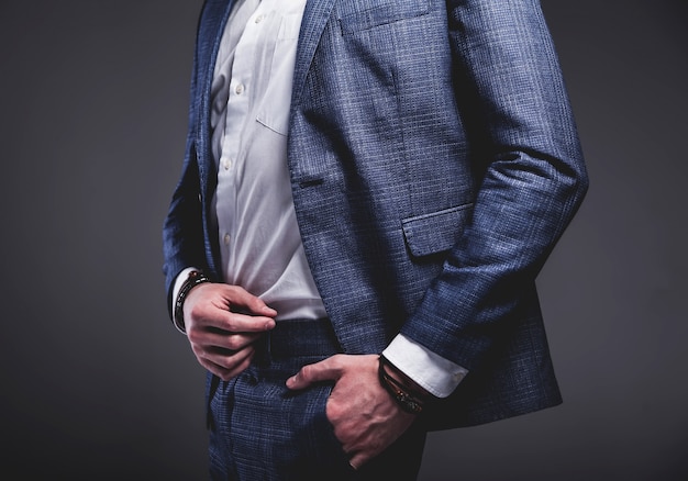 il ritratto del modello dell'uomo d'affari alla moda dei pantaloni a vita bassa alla moda bello si è vestito in vestito blu elegante su gray