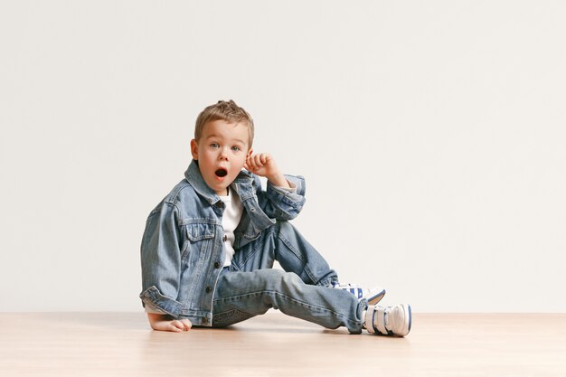 Il ritratto del ragazzo carino bambino in jeans eleganti vestiti guardando la fotocamera