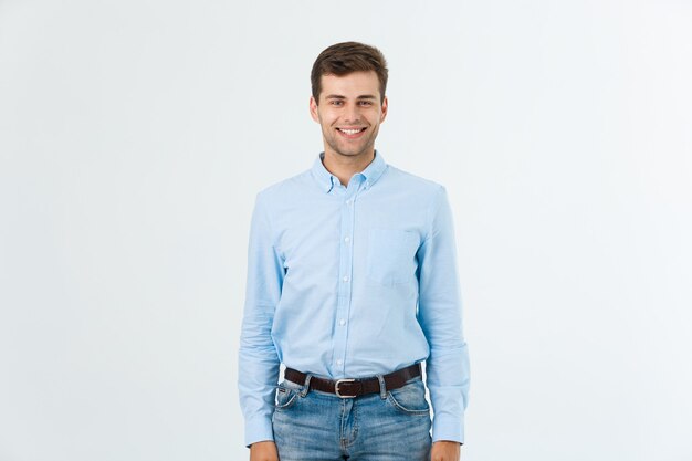 Il ritratto dell'uomo bello alla moda felice in jeans e camicia blu esamina la macchina fotografica.