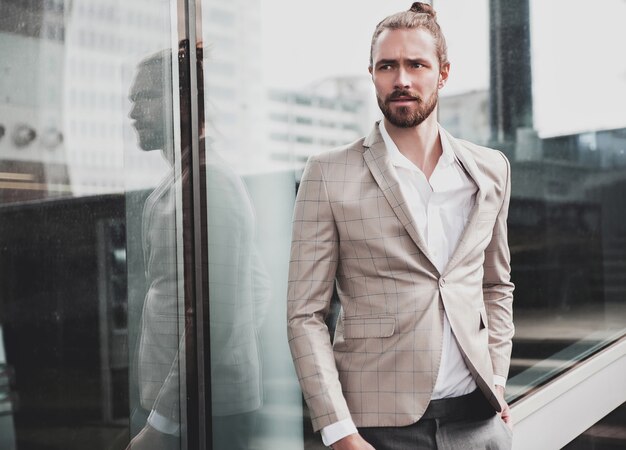 Il ritratto dell'uomo bello sexy si è vestito in vestito a quadretti beige elegante