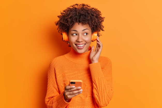 Il ritratto della bella donna afroamericana con i sorrisi dei capelli ricci ha ampiamente denti bianchi perfetti