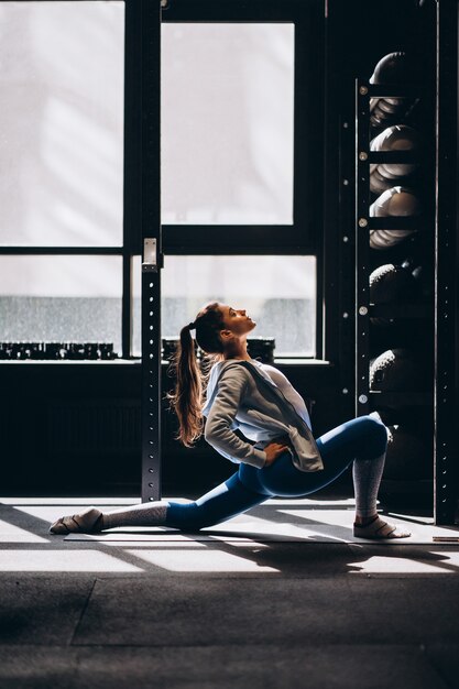 Il ritratto della giovane donna attraente che fa l'yoga o i pilates si esercita