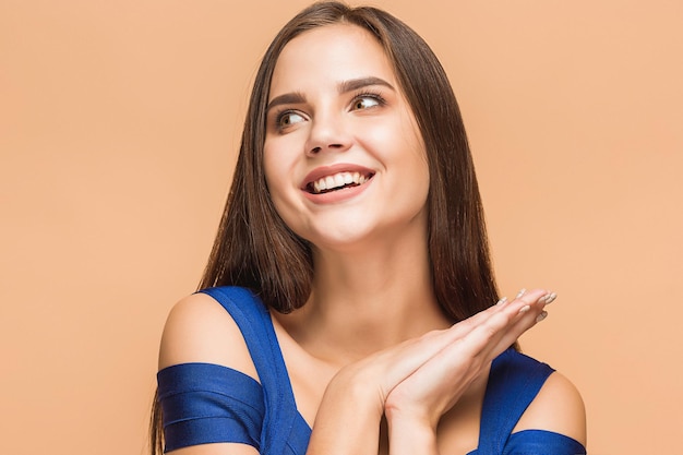 Il ritratto della giovane donna con emozioni felici su sfondo marrone studio