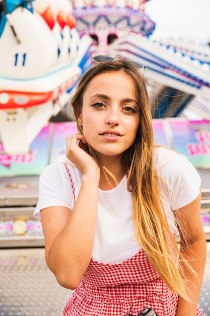 Il ritratto della giovane donna sorridente che sta davanti al parco di divertimenti guida