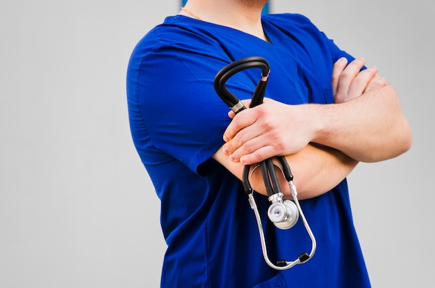 Il ritratto della mano di un medico maschio con il braccio ha attraversato la condizione contro fondo grigio