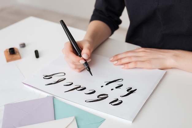 Il ritratto delle mani della giovane donna scrive l'alfabeto su carta sulla scrivania isolata