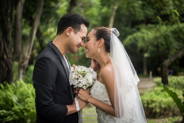 Il ritratto dello sposo di giorno delle nozze di amore dà il mazzo dei fiori alla sua sposa.