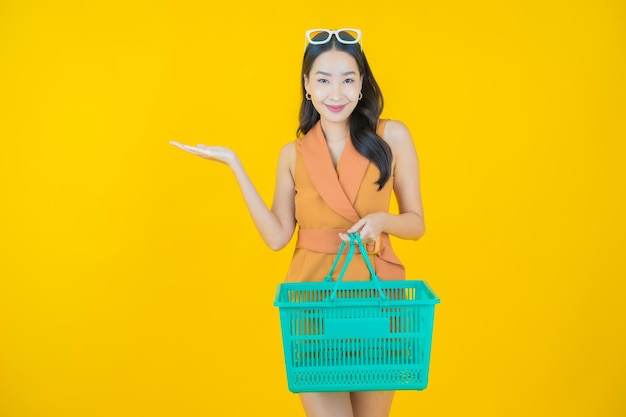 Il ritratto di bella giovane donna asiatica sorride con il cestino della spesa dal supermercato