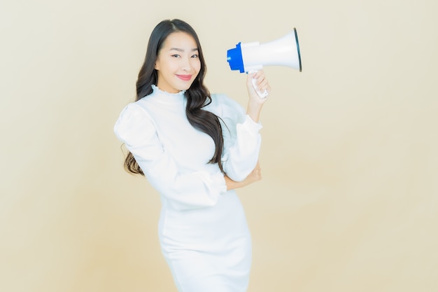 Il ritratto di bella giovane donna asiatica sorride con il megafono sulla parete di colore