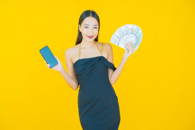 Il ritratto di bella giovane donna asiatica sorride con molti contanti e soldi