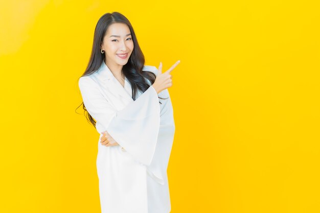 Il ritratto di bella giovane donna asiatica sorride sulla parete gialla