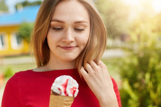 Il ritratto di bella giovane donna con capelli chiari si è vestito in blusa rossa