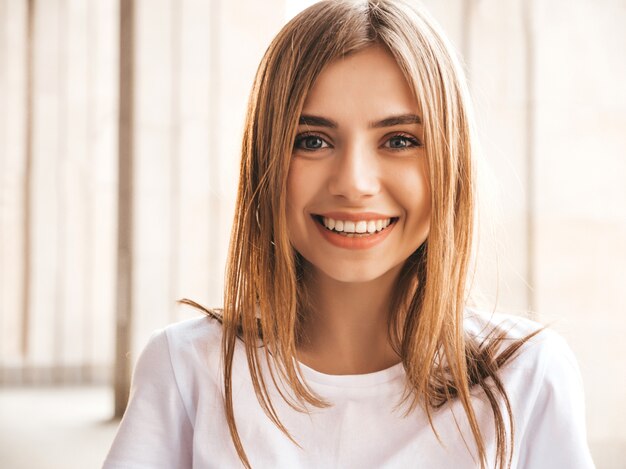 Il ritratto di bello modello biondo sorridente si è vestito in vestiti dei pantaloni a vita bassa dell'estate.