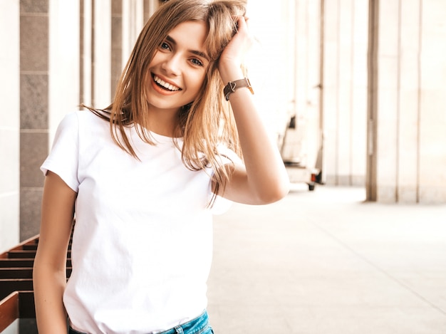 Il ritratto di bello modello biondo sorridente si è vestito in vestiti dei pantaloni a vita bassa dell'estate.