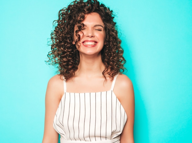 Il ritratto di bello modello sorridente con l'acconciatura dei riccioli di afro si è vestito in vestiti dei pantaloni a vita bassa dell'estate. Donna divertente e positiva alla moda