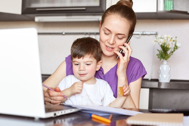 Il ritratto di giovane madre lavora indipendente sul computer portatile