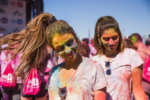 Il ritratto di un amico femminile sorridente due ha coperto il loro fronte di colore di holi