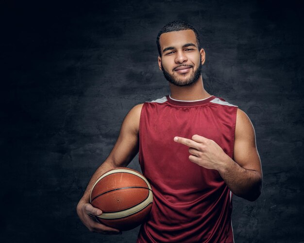 Il ritratto di un uomo di colore barbuto tiene una palla da basket.