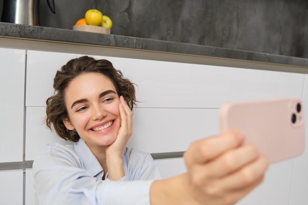 Il ritratto di una bella donna felice scatta un selfie sullo smartphone e allunga la mano con il cellulare e