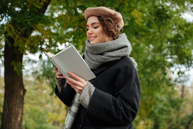 Il ritratto di una ragazza allegra si è vestito nella lettura dei vestiti di autunno