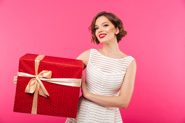 Il ritratto di una ragazza sorridente si è vestito in contenitore di regalo della tenuta del vestito