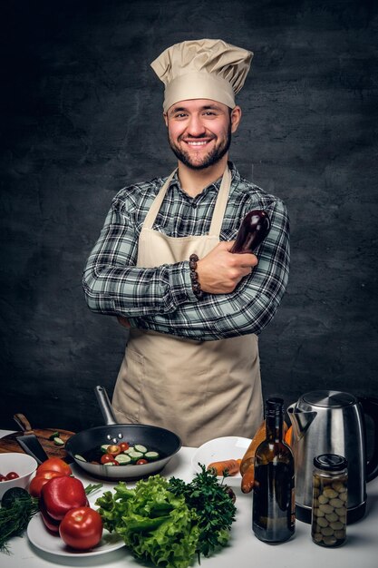 Il ritratto in studio del maschio positivo del cuoco tiene le melanzane.