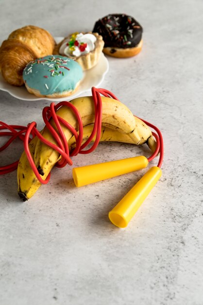 Il salto della corda ha rotolato con la banana e il dessert delizioso sul piatto sopra fondo concreto