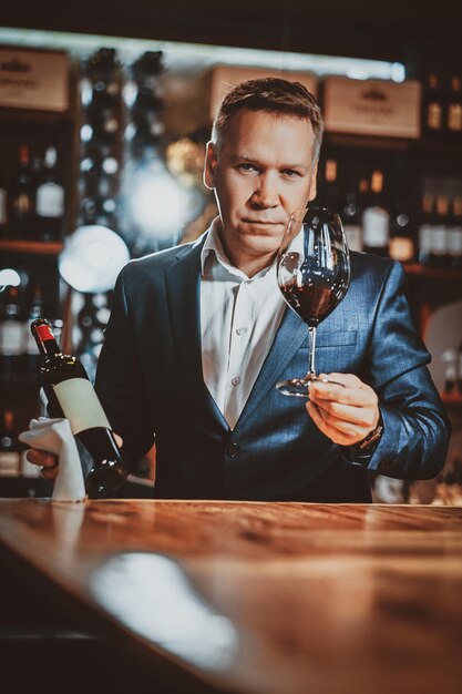 Il sommelier di vino serio ed elegante è pronto per provare il nuovo vino rosso presso la boutique del vino artigianale.