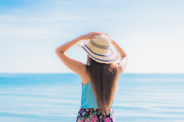 Il sorriso felice della bella giovane donna asiatica del ritratto si rilassa intorno all&#39;oceano ed al mare della spiaggia