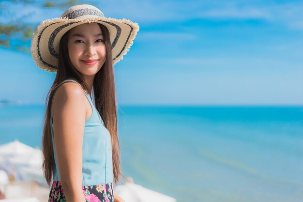 Il sorriso felice della bella giovane donna asiatica del ritratto si rilassa intorno all&#39;oceano ed al mare della spiaggia