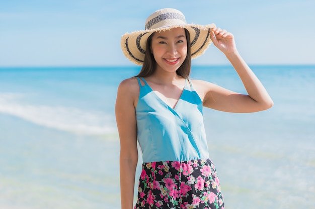 Il sorriso felice della bella giovane donna asiatica del ritratto si rilassa intorno all&#39;oceano ed al mare della spiaggia