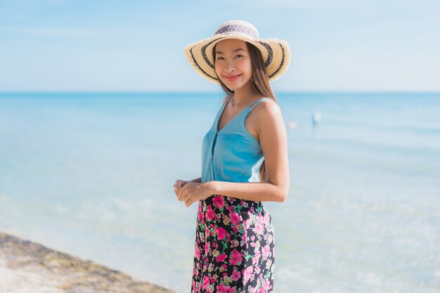 Il sorriso felice della bella giovane donna asiatica del ritratto si rilassa intorno all&#39;oceano ed al mare della spiaggia