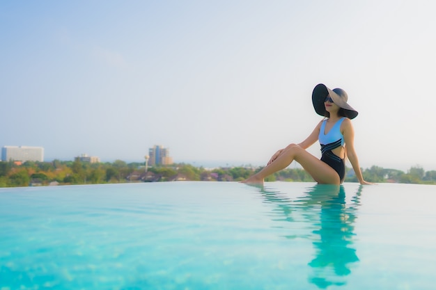 Il sorriso felice della bella giovane donna asiatica del ritratto si rilassa intorno alla piscina all'aperto nella località di soggiorno dell'hotel