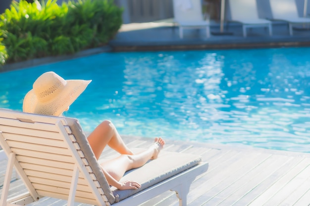 Il sorriso felice della bella giovane donna asiatica del ritratto si rilassa intorno alla piscina all'aperto nella località di soggiorno dell'hotel