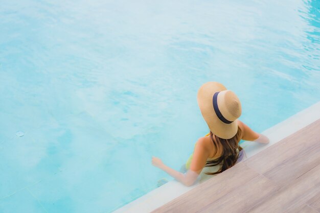 Il sorriso felice della bella giovane donna asiatica del ritratto si rilassa intorno alla piscina all'aperto nella vacanza di festa