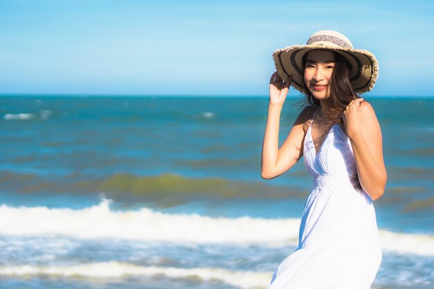 Il sorriso felice della bella giovane donna asiatica del ritratto si rilassa intorno alla spiaggia ed al mare vicini