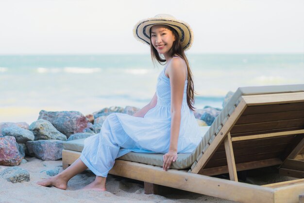 Il sorriso felice della bella giovane donna asiatica del ritratto si rilassa intorno alla spiaggia ed al mare vicini