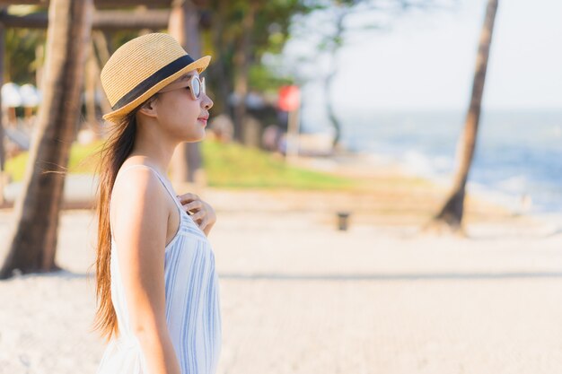 Il sorriso felice della bella giovane donna asiatica del ritratto si rilassa intorno alla spiaggia ed al mare vicini