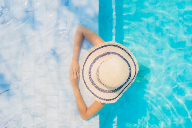 Il sorriso felice della bella giovane donna asiatica del ritratto si rilassa nella piscina per la vacanza di viaggio