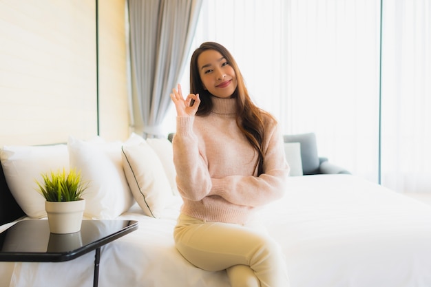 Il sorriso felice della bella giovane donna asiatica del ritratto si rilassa sul letto