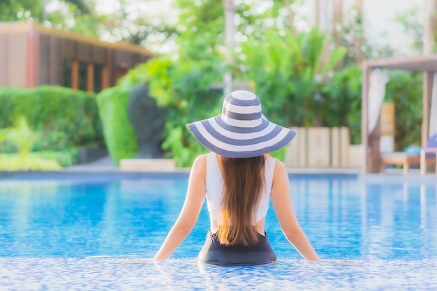 Il sorriso felice della giovane donna asiatica del bello ritratto si rilassa intorno alla piscina nell'hotel di località di soggiorno