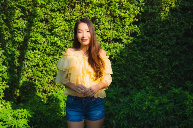 Il sorriso felice della giovane donna asiatica del ritratto si rilassa intorno al giardino all'aperto della natura