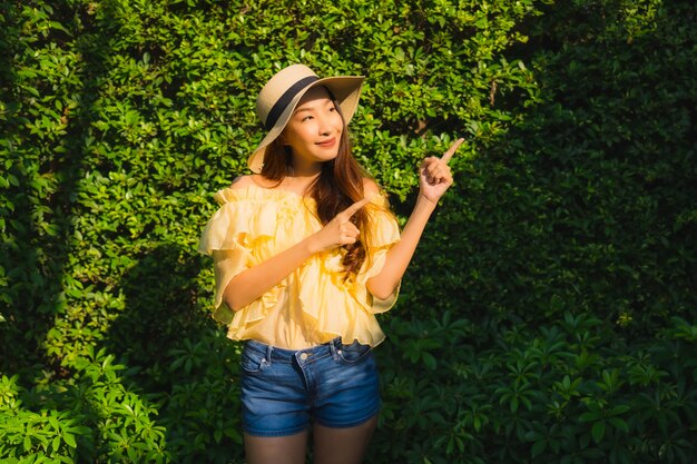 Il sorriso felice della giovane donna asiatica del ritratto si rilassa intorno al giardino all'aperto della natura