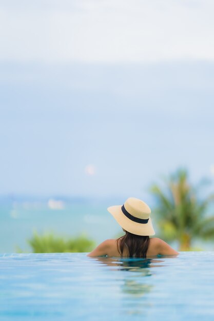 Il sorriso felice della giovane donna asiatica del ritratto si rilassa intorno alla piscina nella località di soggiorno dell'hotel