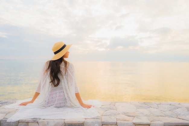 Il sorriso felice delle belle giovani donne asiatiche del ritratto si rilassa intorno all'oceano della spiaggia del mare