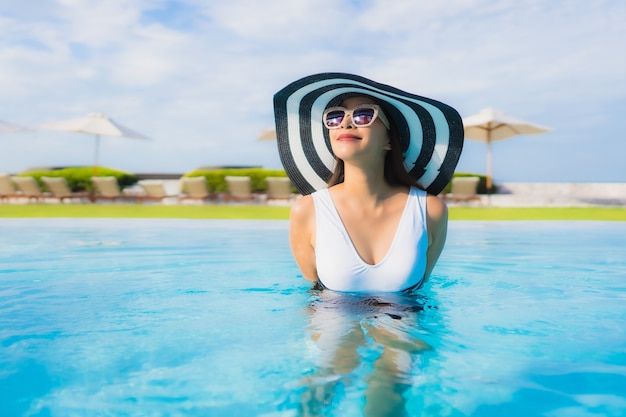 Il sorriso felice delle belle giovani donne asiatiche del ritratto si rilassa intorno alla piscina