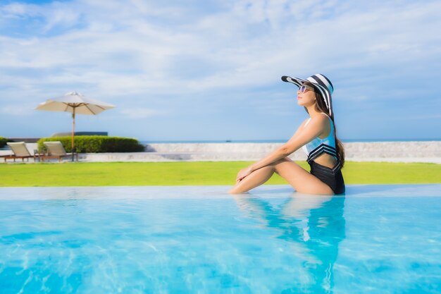 Il sorriso felice delle belle giovani donne asiatiche del ritratto si rilassa intorno alla piscina