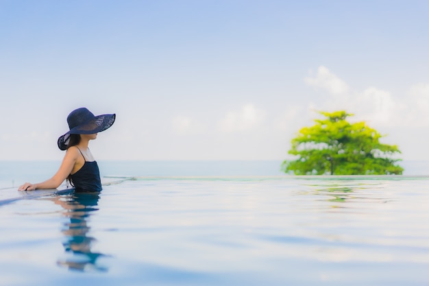 Il sorriso felice delle belle giovani donne asiatiche del ritratto si rilassa la piscina all'aperto in hotel